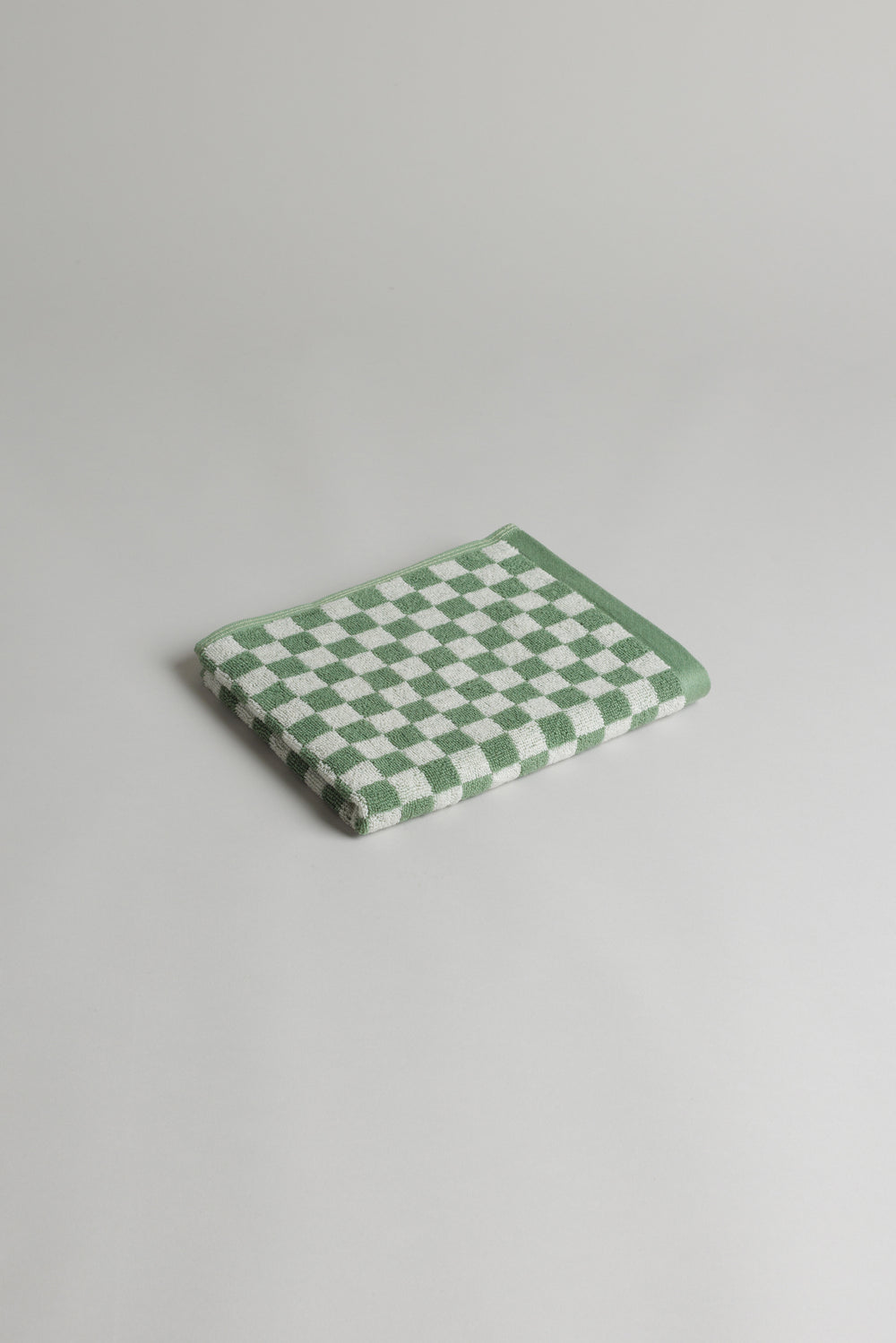 Baina Josephine hand towel in sage and chalk with soft, textured fabric, displayed on a bathroom hook.