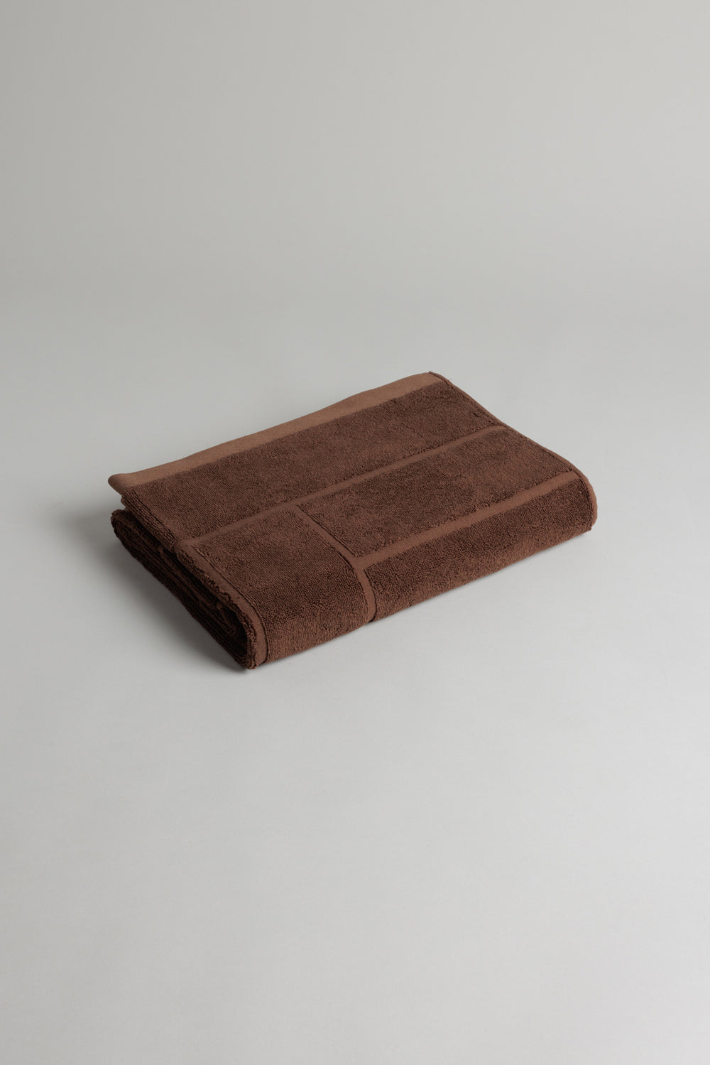 Baina Greenwich bath towel in Tabac color, soft and plush, shown folded on a clean bathroom surface.