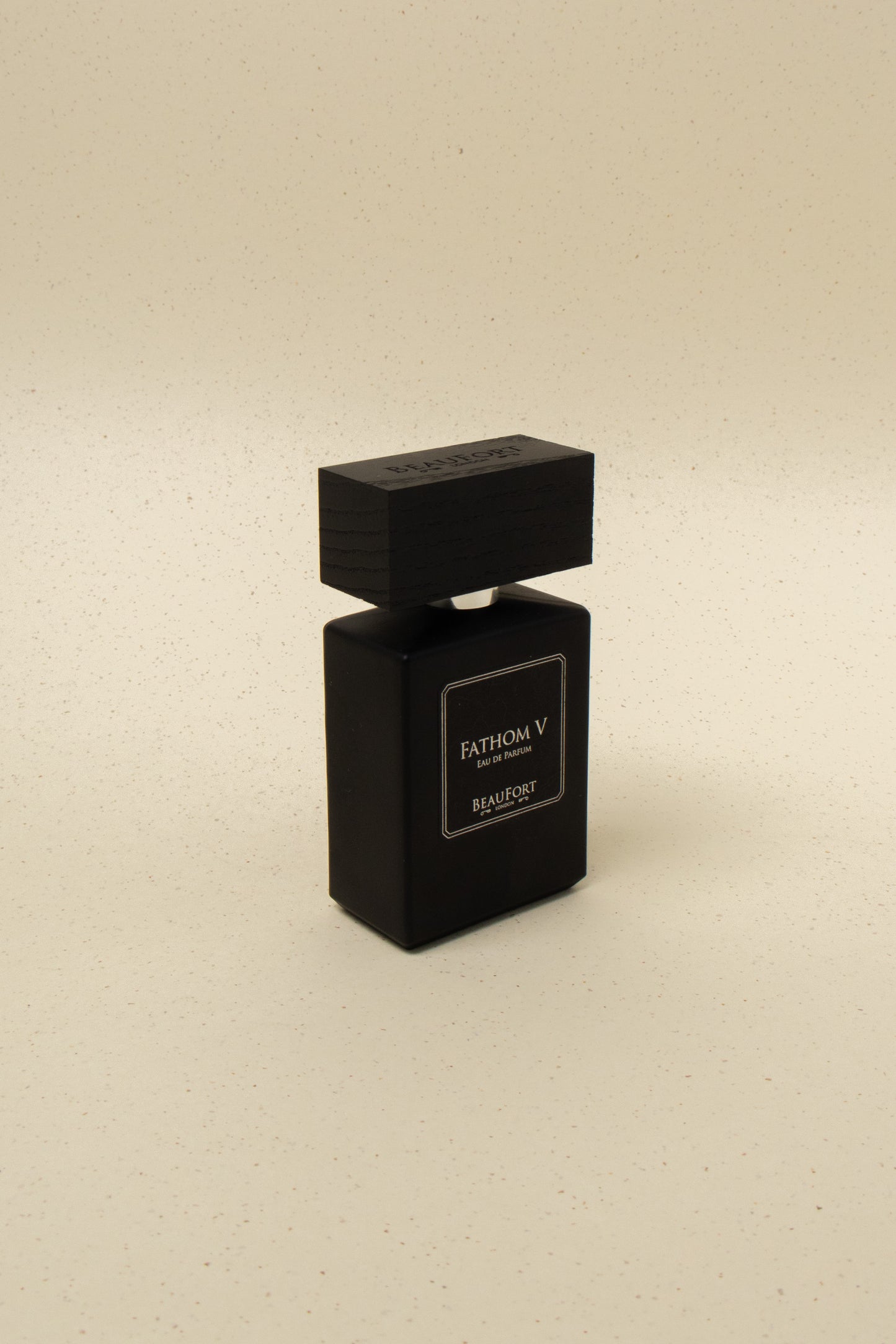 Black BeauFort Fathom V eau de parfum bottle with a wooden cap on beige speckled background
