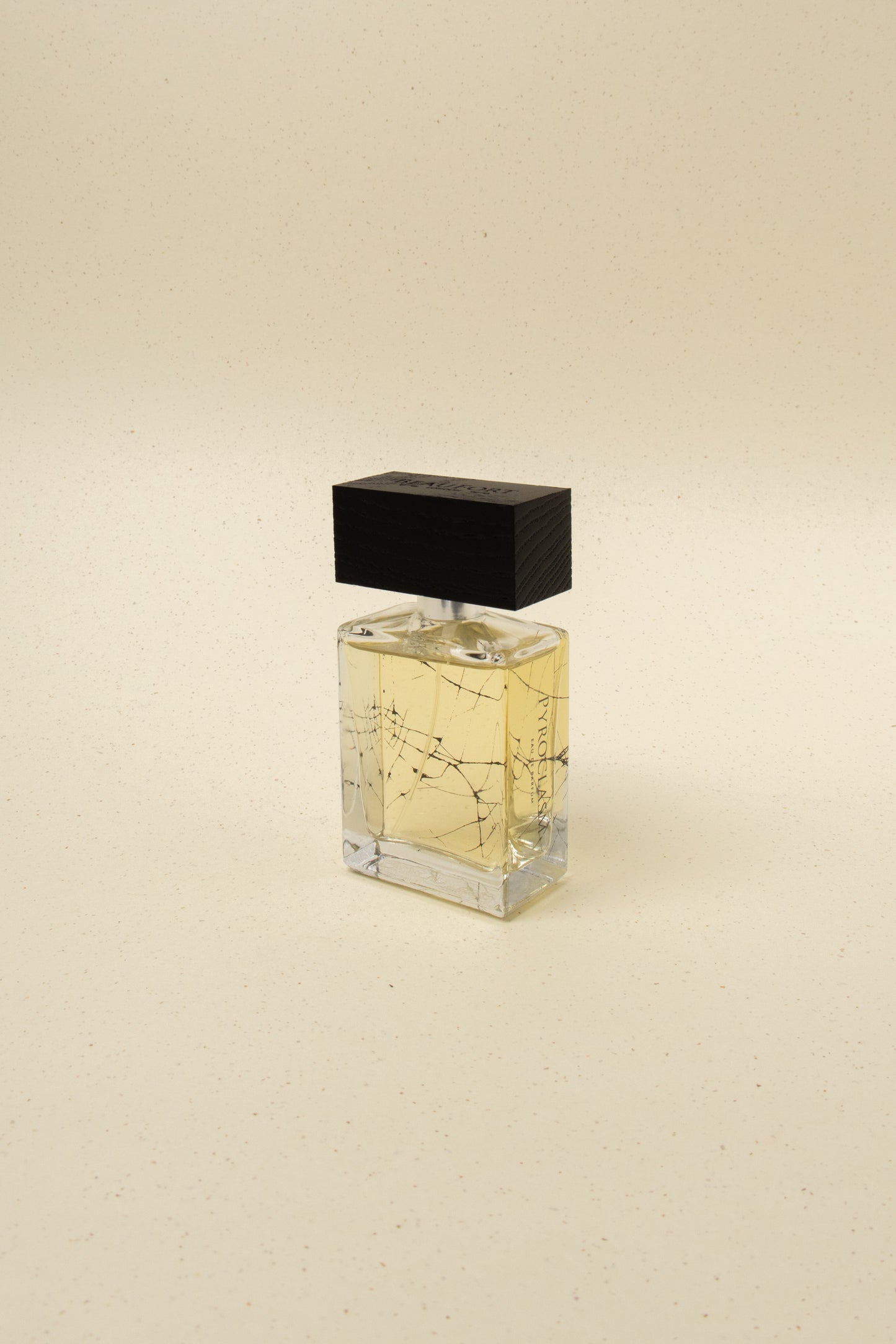Pyrologist niche perfume bottle with black wooden cap on beige speckled background