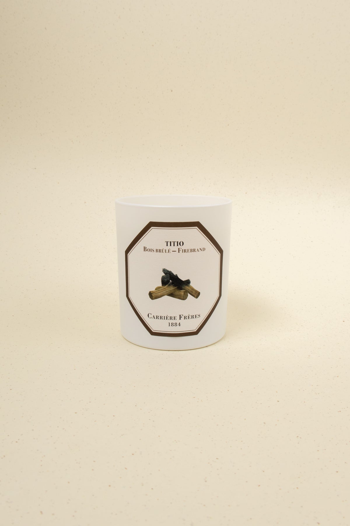 Carrière Frères Firebrand scented candle with a decorative glass jar and warm flame, emitting a cozy, inviting glow.