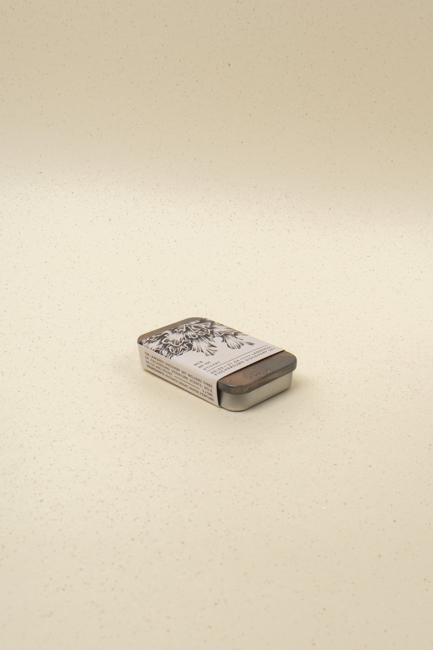 Fischersund Langdegi Discovery Set in compact metal tin with black floral design, minimalist beige background