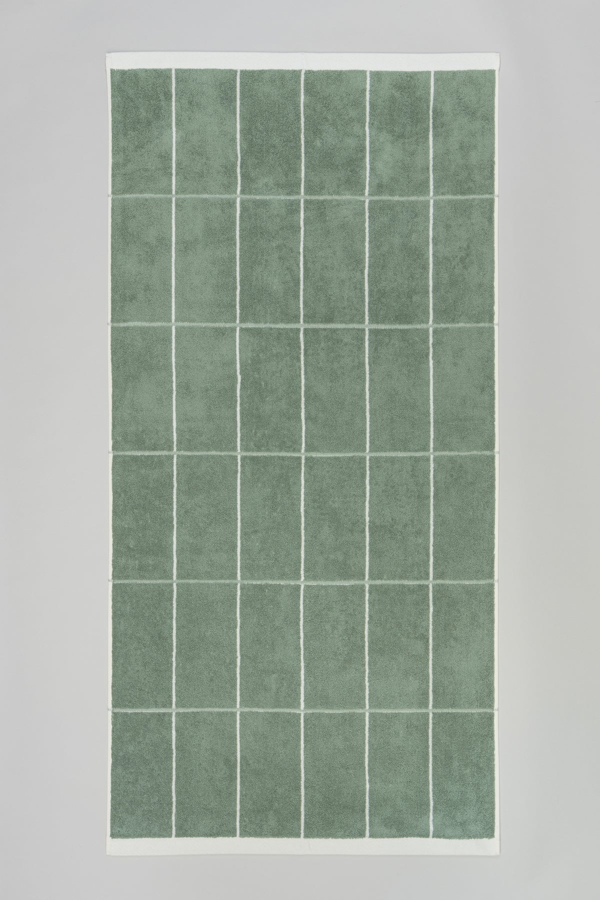 BAINA Bethell bath towel in sage and chalk colors, soft and plush, shown in flatlay with folded design and textured fabric.