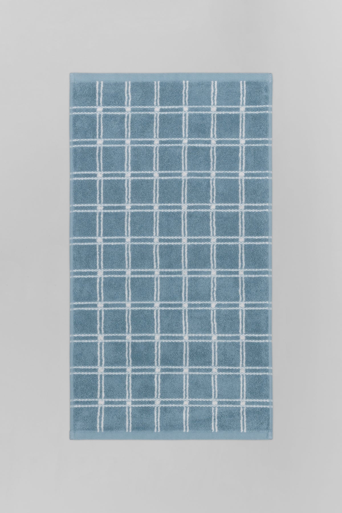 Baina Ness hand towel in Celeste and Chalk colors, folded flat, showcasing soft, absorbent fabric and stylish design.