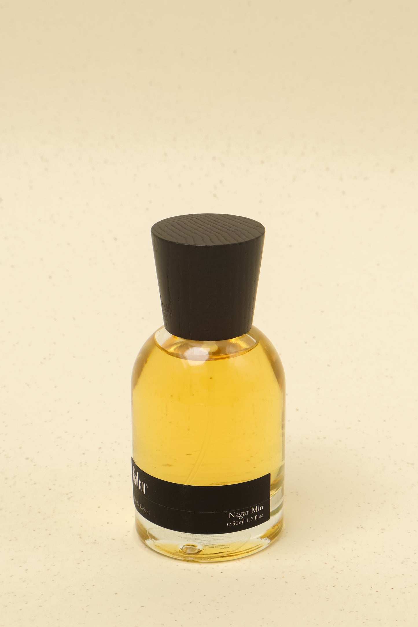 50ml artisanal perfume bottle labeled Nagar Min with black wooden cap on beige background
