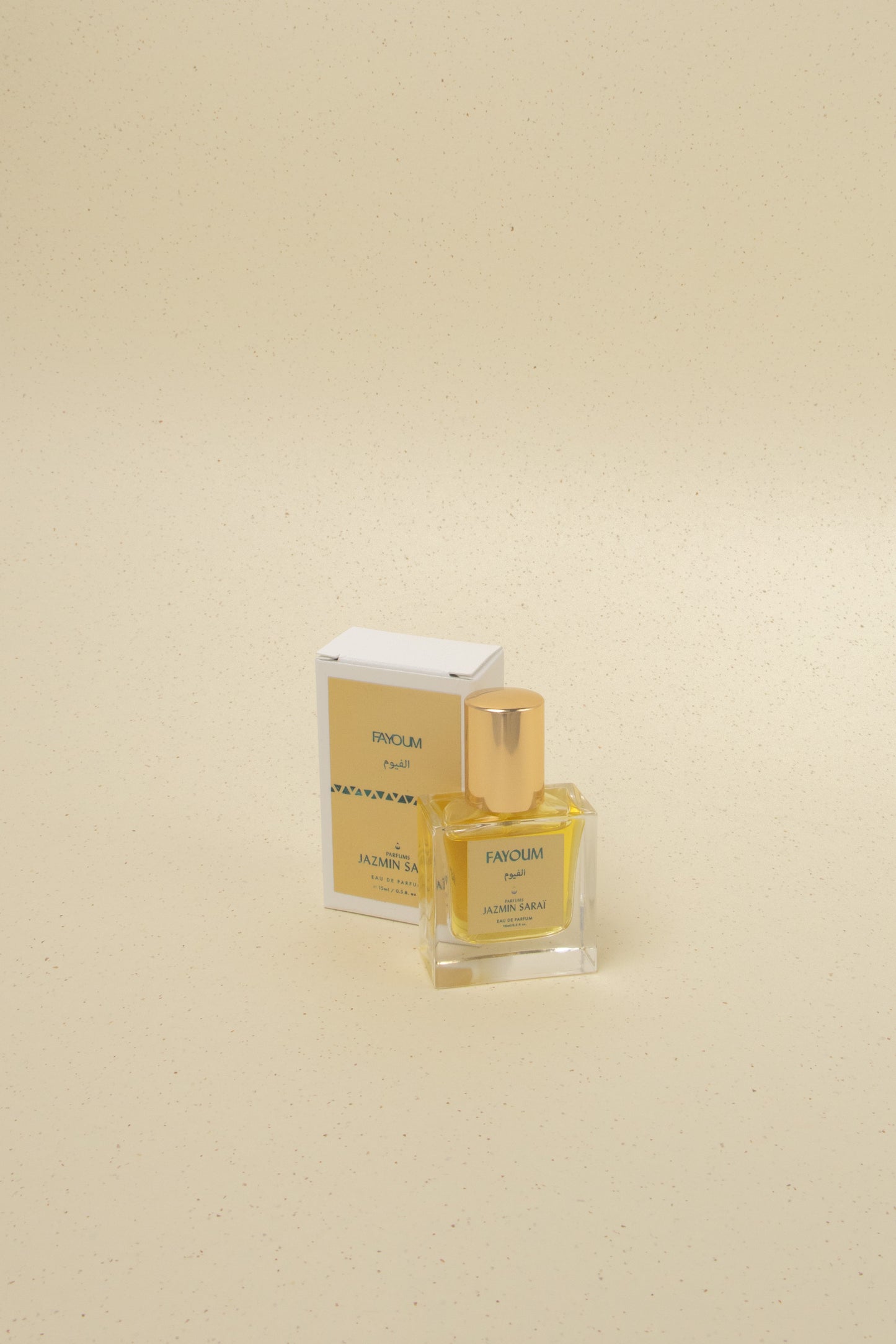 Fayoum Jazmin Sarai Eau de Parfum bottle with gold cap and matching box on beige speckled background