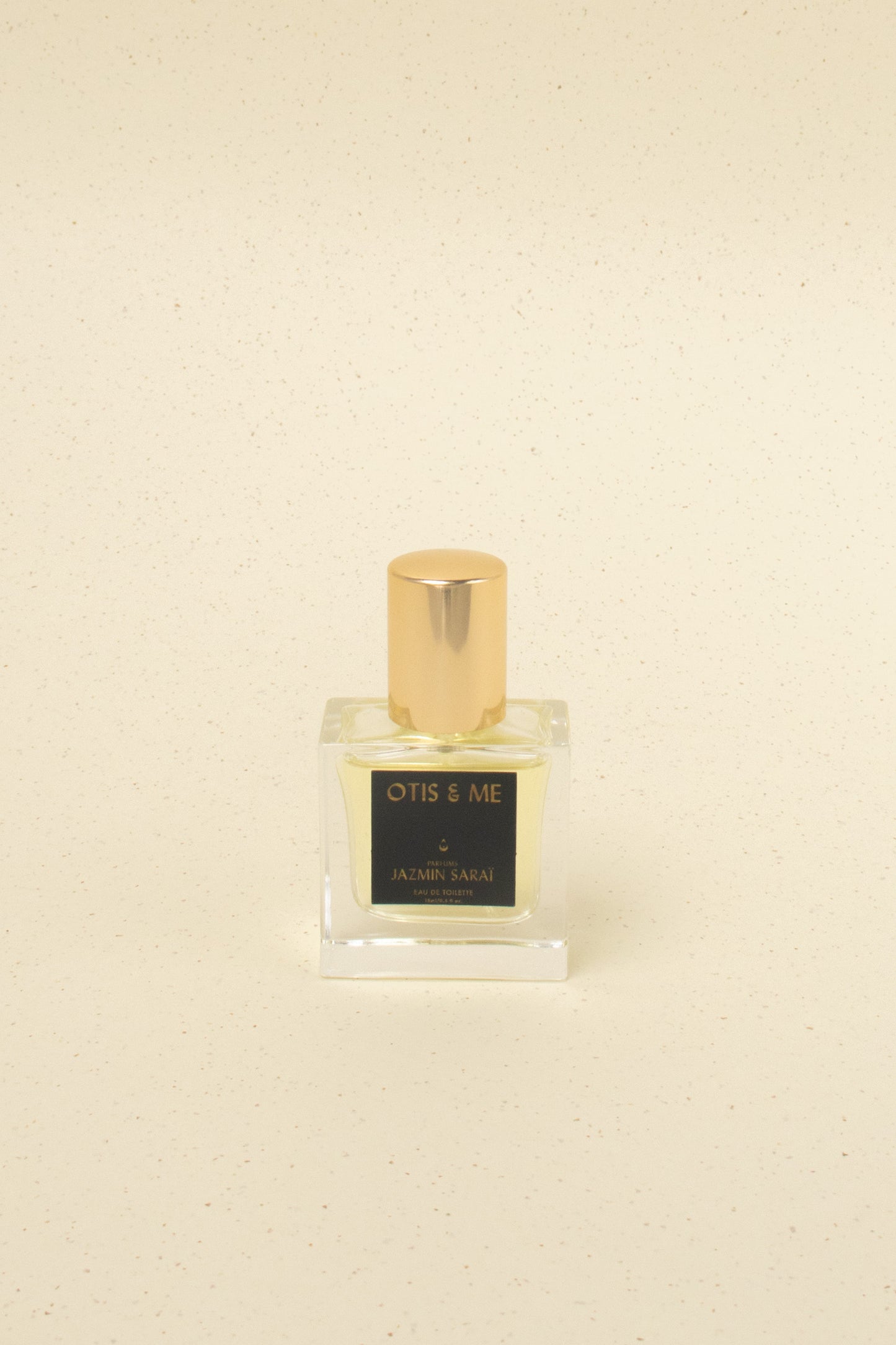 Otis & Me Jazmin Sarai eau de toilette perfume bottle with gold cap on beige speckled surface