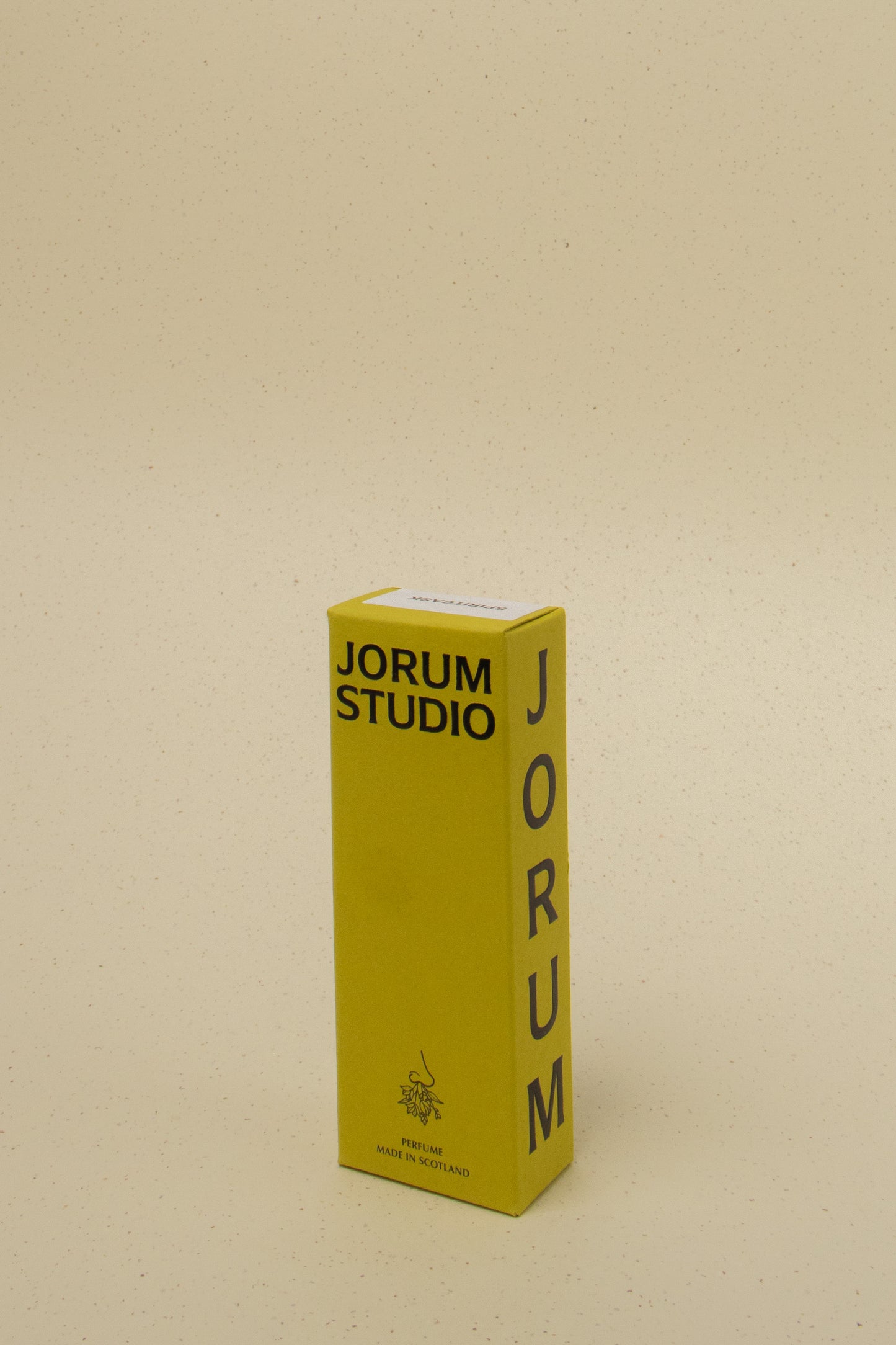 Yellow Jorum Studio perfume box with black text, made in Scotland, on beige speckled background
