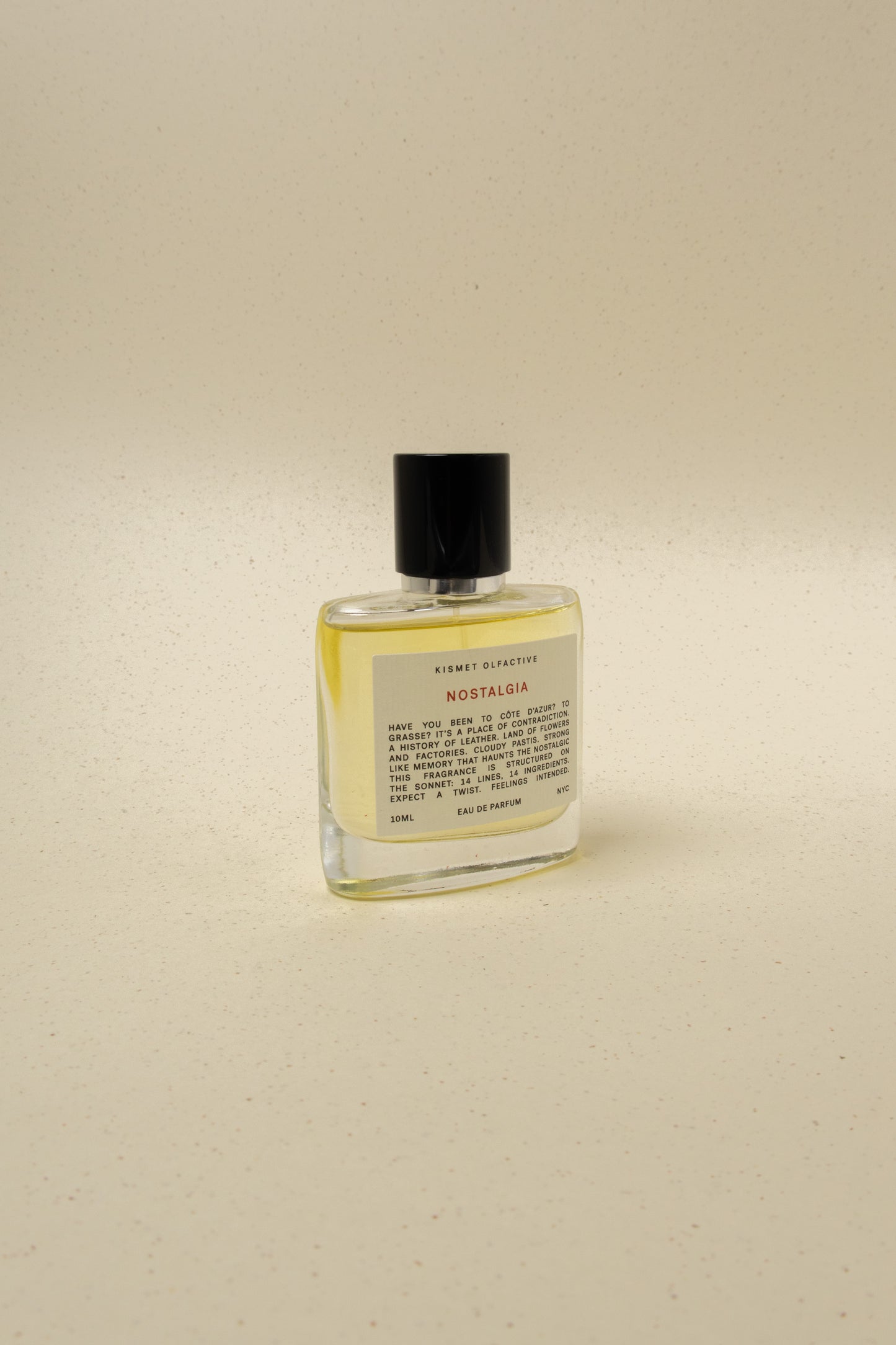 Kismet Olfactive Nostalgia 10ml eau de parfum bottle with black cap on beige speckled background