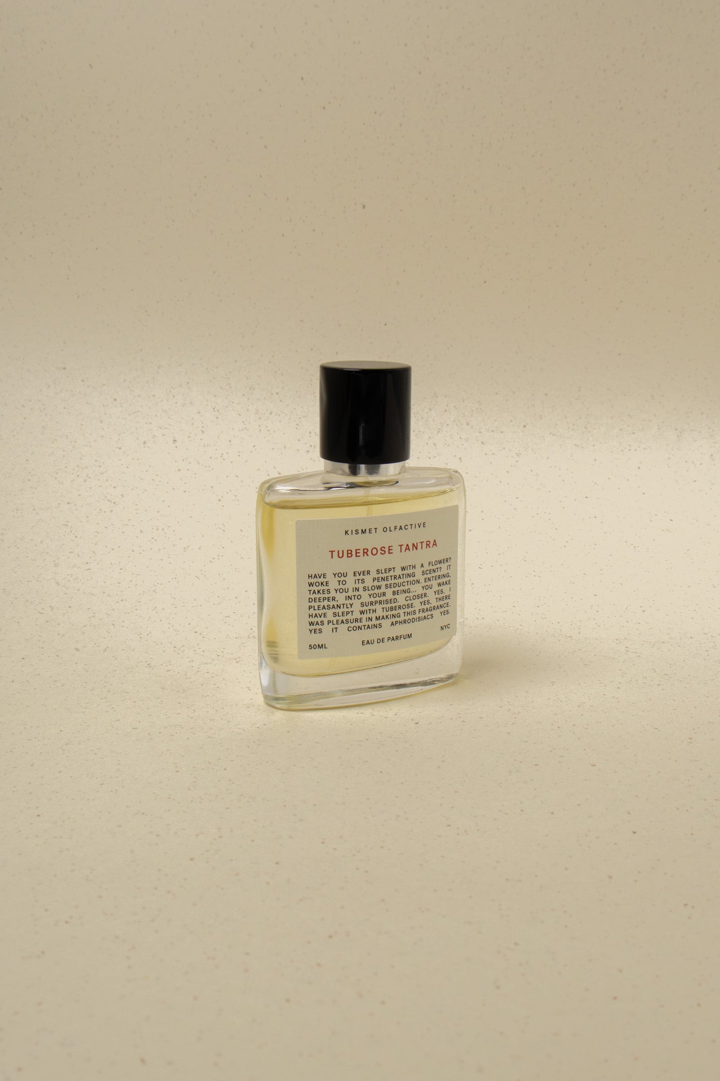 Kismet Olfactive Tuberose Tantra perfume bottle with black cap on beige speckled background