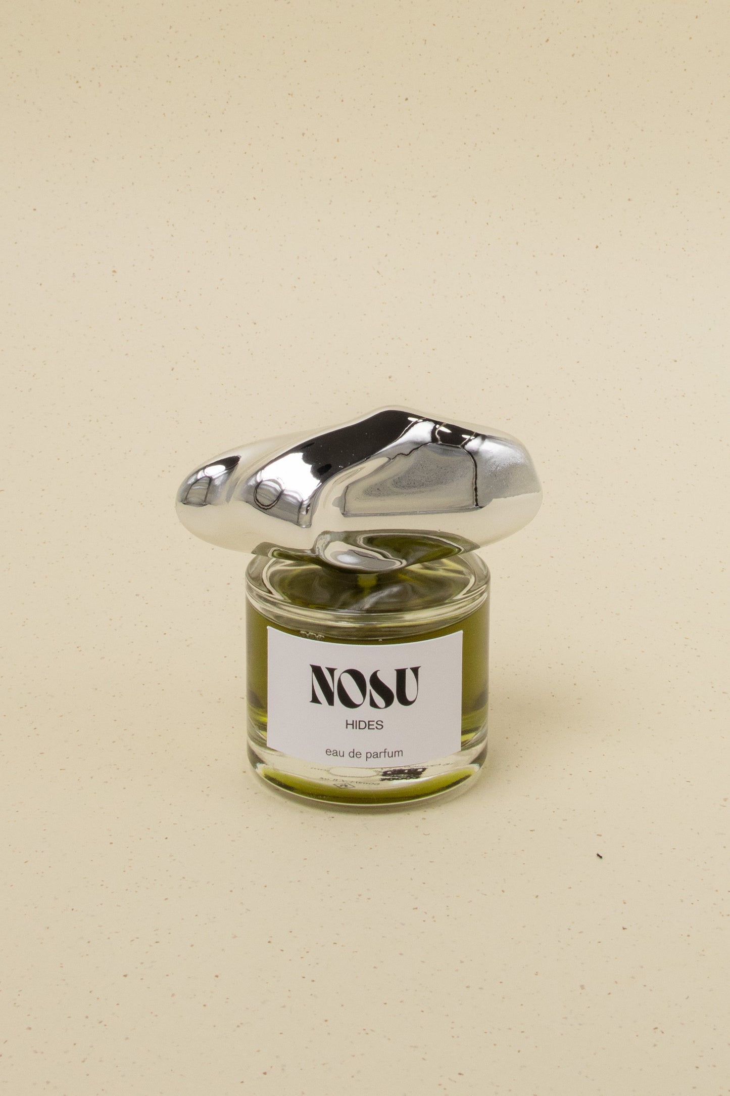 Nosu Hides eau de parfum with unique polished silver cap on beige background