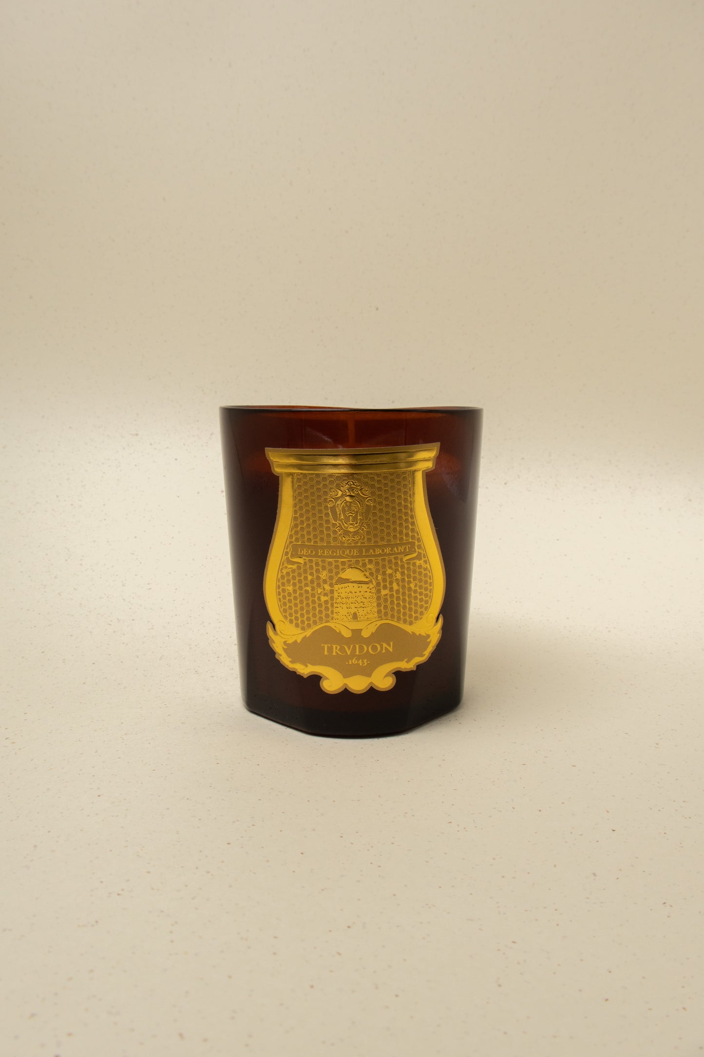 Trudon 270g luxury scented candle in dark amber glass with gold detailed label, artisan fragrance